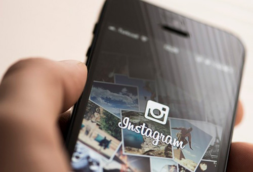 Descrição da imagem: mão segurando smartphone onde se vê o aplicativo do instagram.